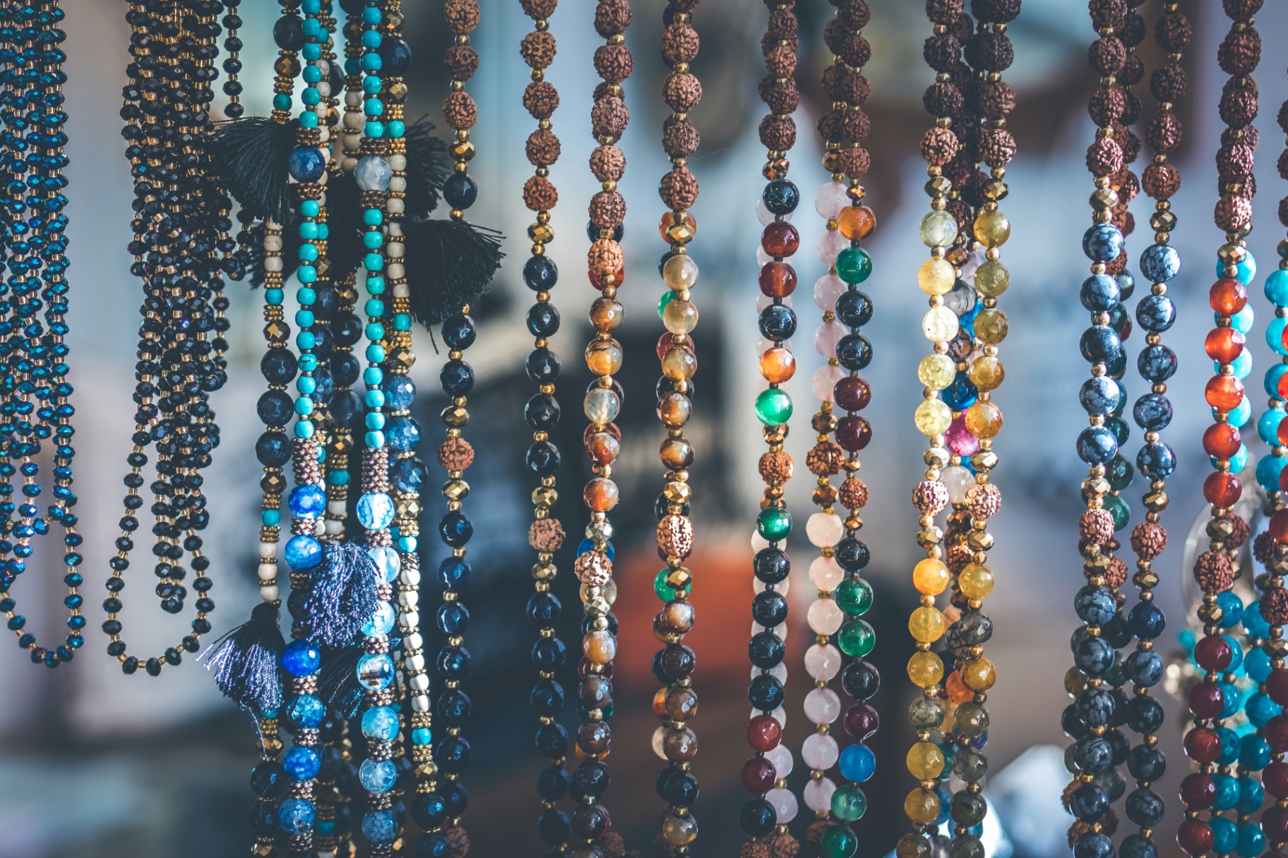 Strands of mala beads in agate, rudraksha and turquoise hanging in soft light